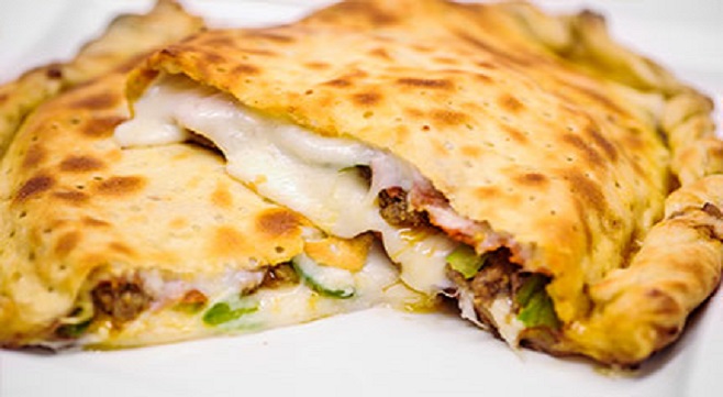 A baked calzone cut open to show its filling